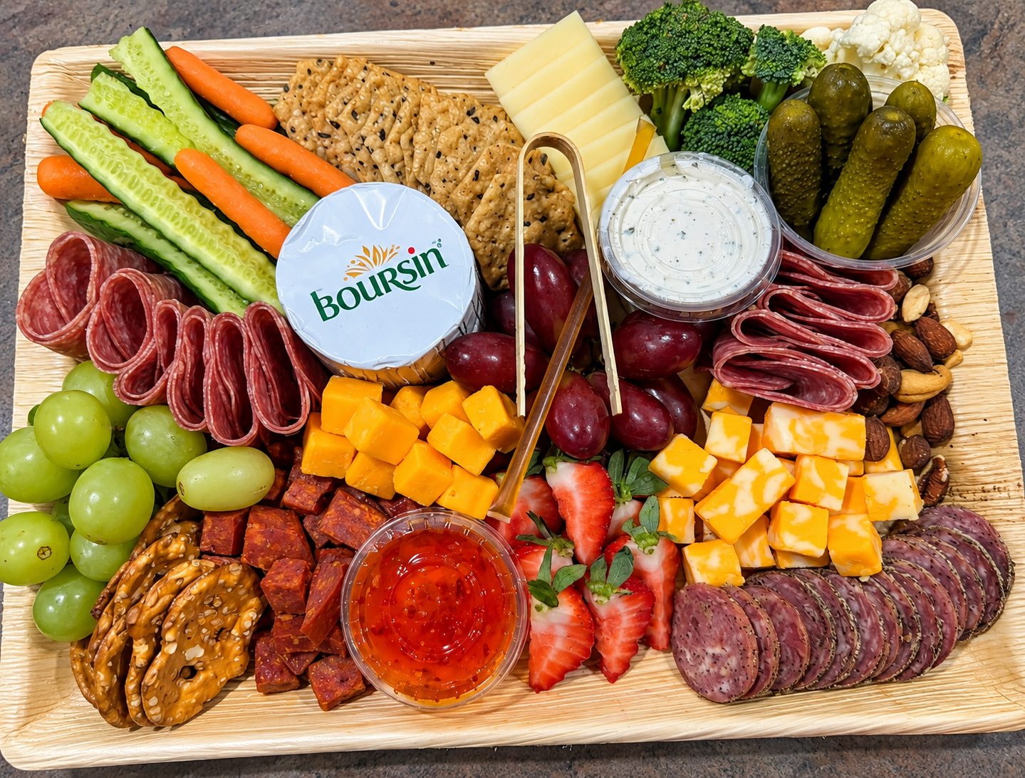 Large charcuterie board with Boursin cheese, vegetables, and meats